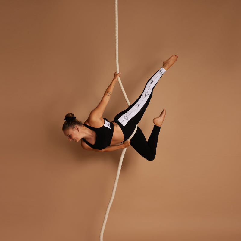 female aerialist doing a balance trick on rope in Signature Aerial leggings and bra